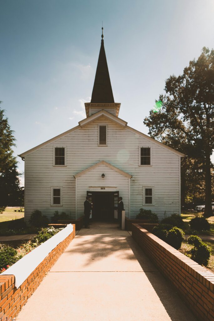A picturesque chapel with a steeple and wooden architecture set in the countryside under clear skies.